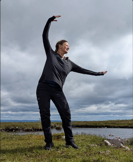 Jenny stretching outdoors under cloudy sky