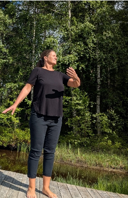Jenny standing in nature practicing Tai Chi